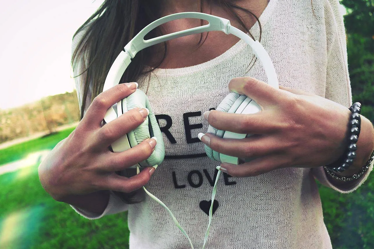 Frau hält weiße Over-Ear Kopfhörer in der Hand