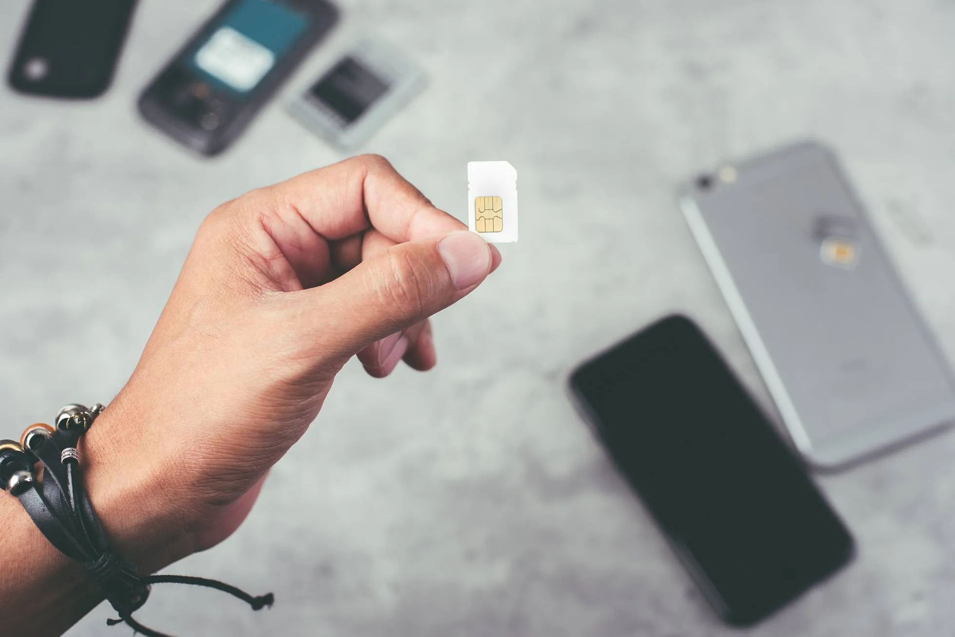 Mann hält Simkarte vor einem Smartphone in der Hand