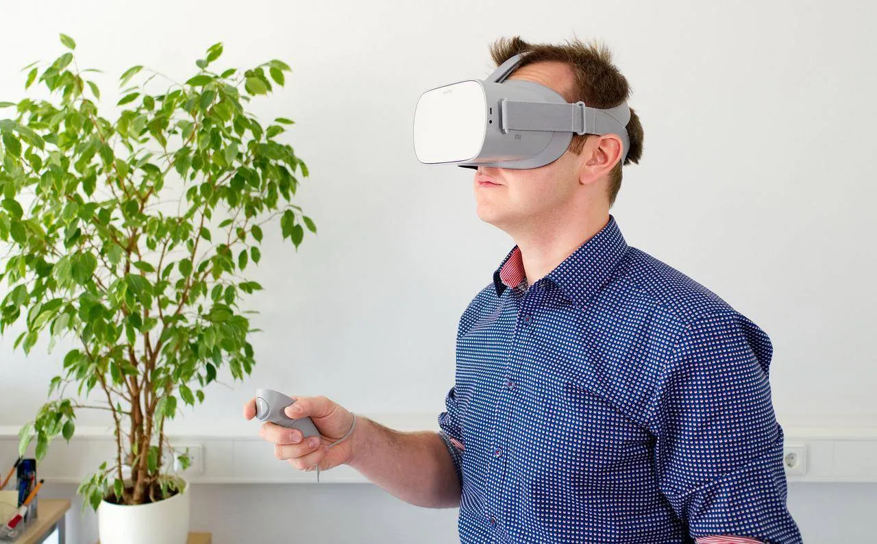 Mann mit VR Brille und Controller im Wohnzimmer